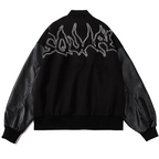 Black 2KWRLD varsity jacket with white sleeves, ribbed collar, cuffs, and waistband, featuring embroidered patches and button closures.