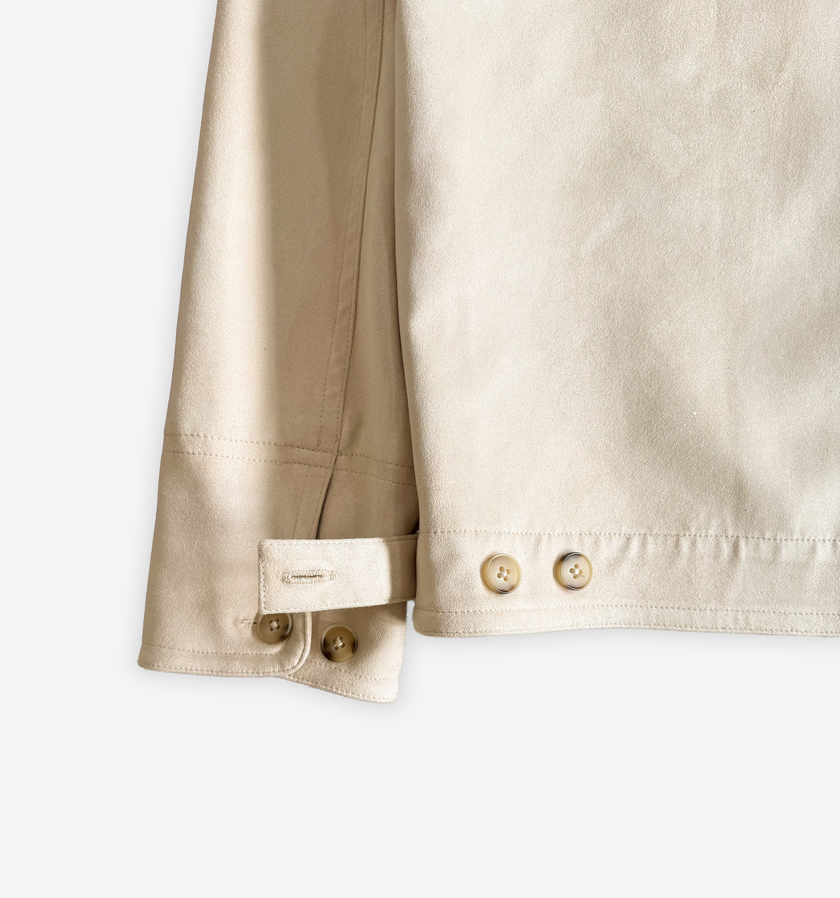 Close-up of the cuff hem of a stylish suede jacket V2 by 2K WRLD, showing detailed stitching and soft suede texture.