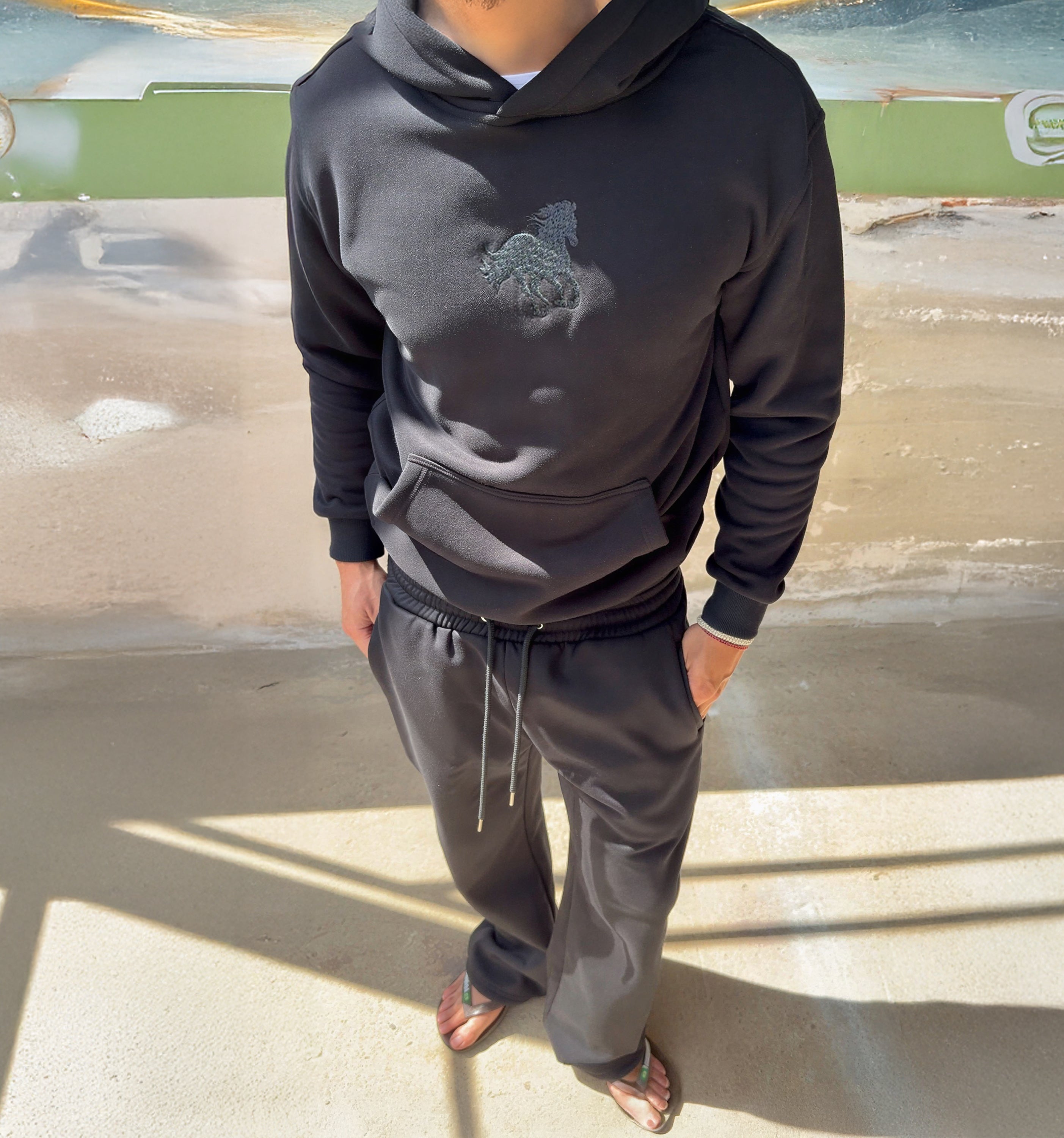 Model wearing the black Melas Hoodie by 2KWRLD, featuring a relaxed fit with a front pocket and drawstring hood.