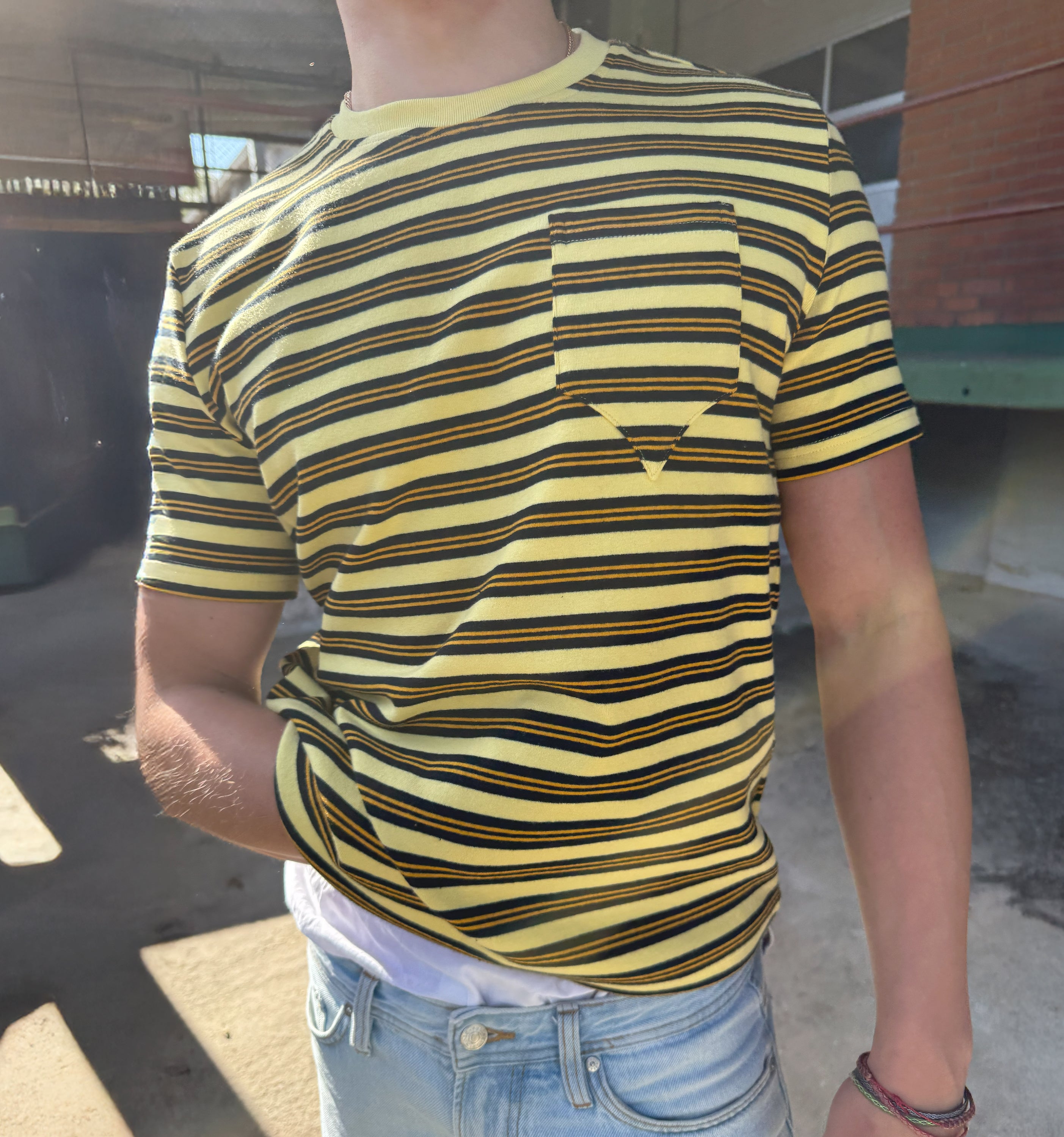Yellow 2K WRLD logo on a model's body, showcasing vibrant branding on a sleek apparel piece.